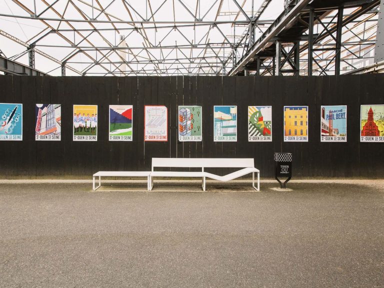 a bench in front of a wall with posters on it